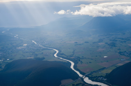 Aerial view from airplane window on the river and mountains with cloudsの素材
