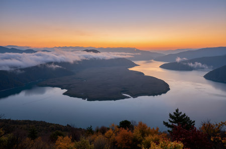 Autumn landscape of the lake and mountains in the fog at sunriseの素材