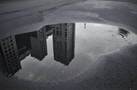 Reflection of a building in a puddle on the ground.の素材
