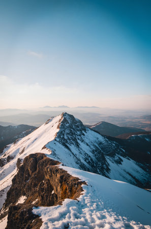 Mountain landscape with snow covered peaks and blue sky at sunset.の素材