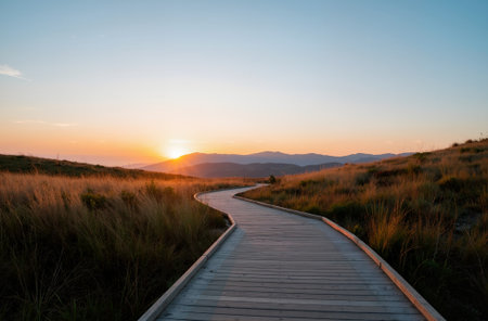 Wooden boardwalk in the dunes at sunset with mountains in the backgroundの素材