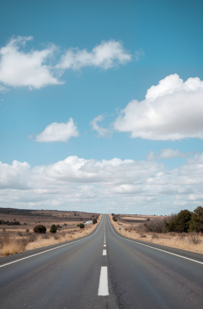 Long straight road with blue sky and white clouds in the background.の素材