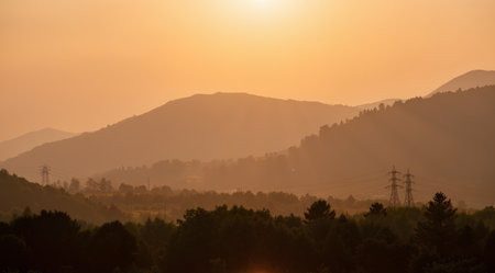 Sunset in the mountains with high-voltage lines and forestの素材