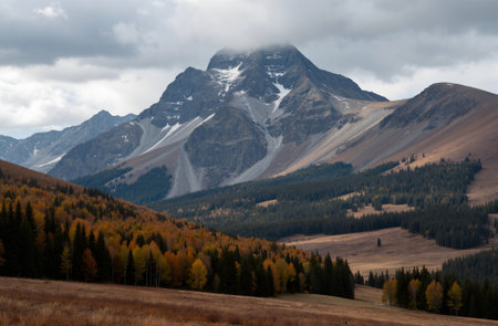 Mountain landscape with yellow autumn trees and snow-capped peaksの素材