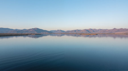 Reflection of the mountains in the water of a lake at sunsetの素材