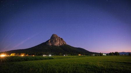 Mountain at night with starry sky and green meadow.の素材