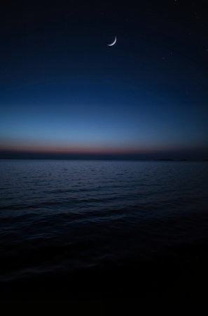 Moon and stars over the sea at night. Long exposure photo.の素材