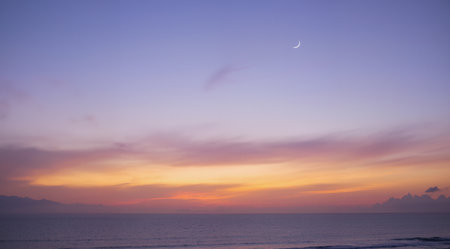 Beautiful sunset over the sea with crescent moon in the skyの素材