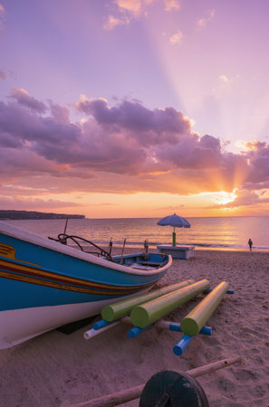Beautiful sunset on the beach with a fishing boat and umbrellasの素材