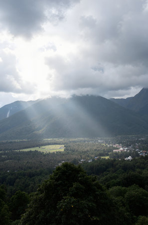 Sun rays through the clouds over the village of Krasnaya Polyana, Sochi, Russiaの素材