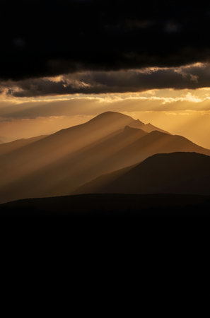 Sunset in the mountains with sunbeams shining through the cloudsの素材