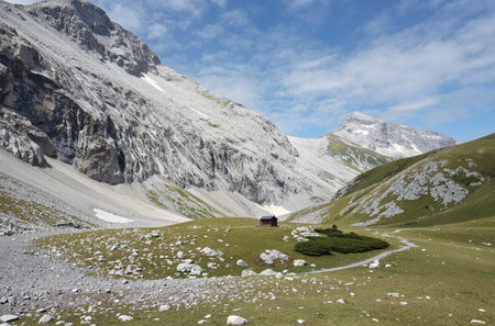 Mountain landscape with small wooden house in the middle of mountain valleyの素材