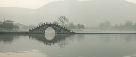 Lake and bridge in foggy morning, Hangzhou, China.の素材