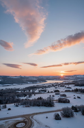 Aerial view of winter landscape with road and forest at sunset.の素材