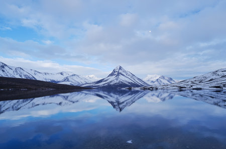 Landscape view of snow capped mountains reflected in the calm lake.の素材