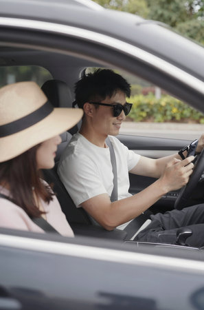 Young couple driving a car, focus on the driver's wheel.の素材