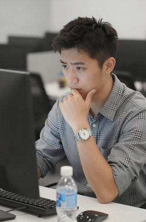Portrait of young Asian businessman working on computer at modern office.の素材