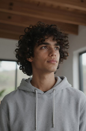 Portrait of a young man with curly hair looking at the cameraの素材