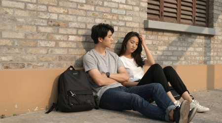 young sad and depressed Asian Korean couple sitting outdoors feeling desperate and desperate suffering depression problem and anxiety crisis problem in social problem and problemの素材