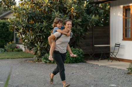 Mother and son having fun in the backyard of their house. They are playing with a piggyback.の素材