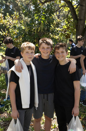 Portrait of happy boys with plastic bags in park on sunny dayの素材