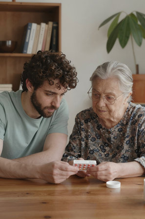 Elderly woman playing cards with her adult son at home.の素材