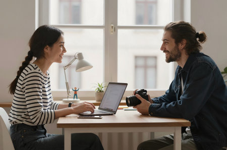Professional photographer working with female colleague in office. Man and woman sitting at desk and looking at each other. Business meeting conceptの素材