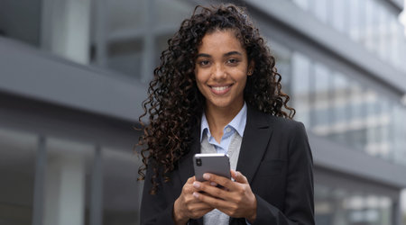 Portrait of young businesswoman sending text message on mobile phone outdoorsの素材