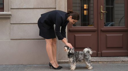 Young woman in black dress walking with her dog on the street.の素材