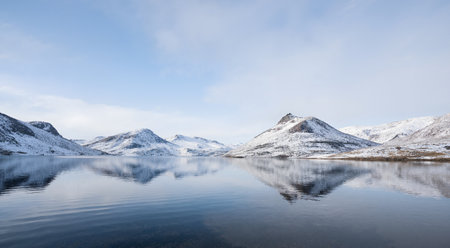 Panoramic view of a mountain lake in winter with snow and reflectionの素材