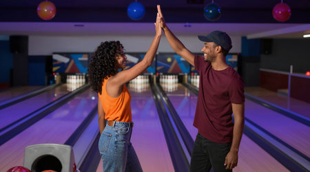 Young african american man and woman playing bowling together at the clubの素材