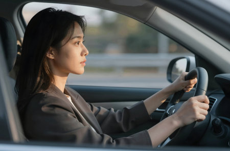 Businesswoman driving a car and looking at the road with serious faceの素材