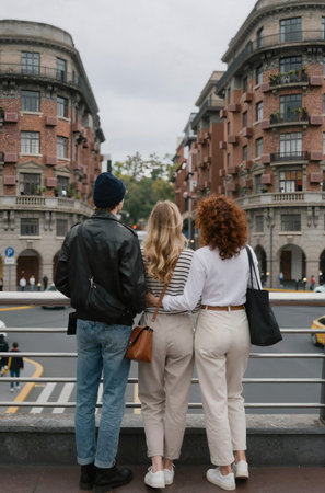 Rear view of three friends standing on street and looking at each otherの素材