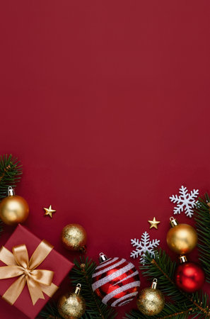 Christmas or New Year background with fir branches, red gift box, gold balls and snowflakes. Top view with copy space.の素材