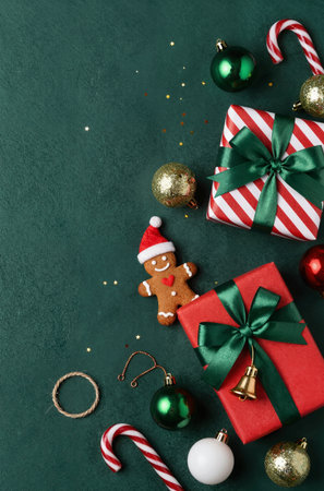 Christmas background with gingerbread man, gift box and christmas decoration on greenの素材
