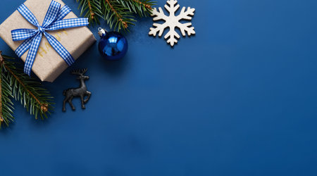 Christmas background with gift box and fir tree branches on blue background.の素材