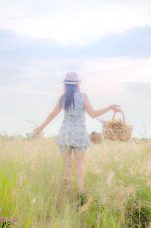 Woman walking in the grass field on sunset.の写真素材