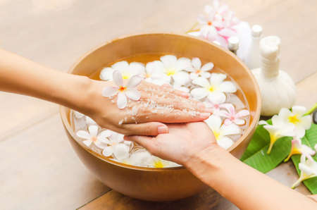 Spa treatment and product for hand spa with flowers and water, wooden background; select and soft focus.の写真素材