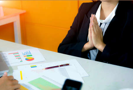 Beautiful business woman with greets/goodbye; in traditional way with both hands in the office.の写真素材