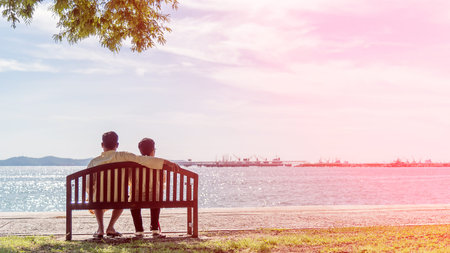 The back of senior couple watching sea; sitting on a chair at the beach; soft and select focus.の写真素材