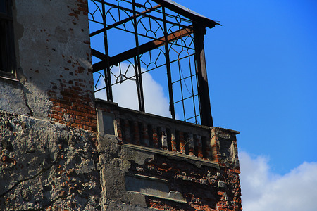 the destroyed brick balcony against the blue skyの写真素材
