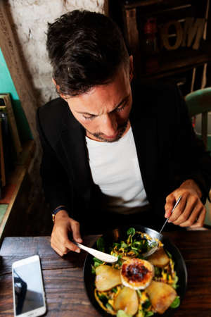 A young vegetarian man eating a salad in an urban pubの写真素材