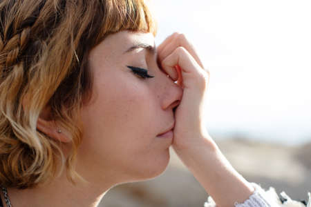 A young blonde beautiful woman thinking with eyes closedの写真素材