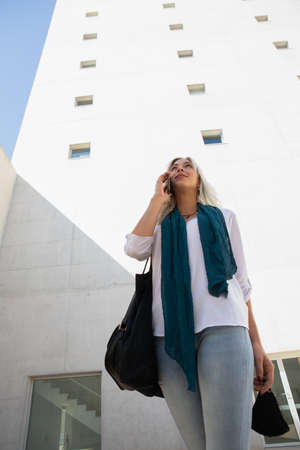 a confident professional young blonde woman using a smartphone outdoorsの写真素材