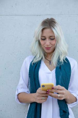a confident professional young blonde woman using a smartphone outdoorsの写真素材