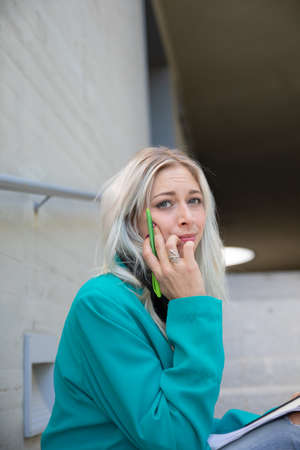 a professional young blonde woman worried outdoorsの写真素材