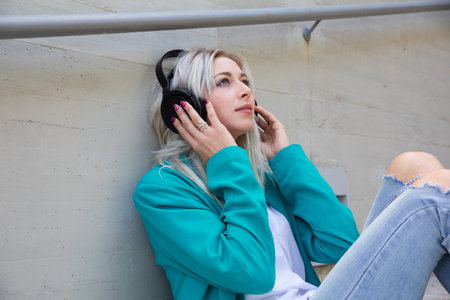 a young blonde woman chilling and enjoying music with headphonesの写真素材