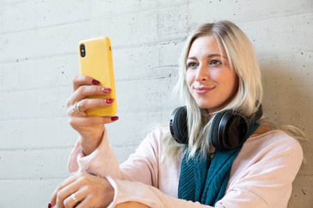 A young beautiful blonde student woman using a smartphone in the university