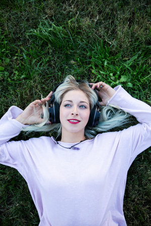 a young blonde woman chilling and enjoying music with headphones