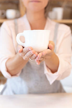 An Attractive professional craftswoman offering a cup of tea or coffeeの写真素材